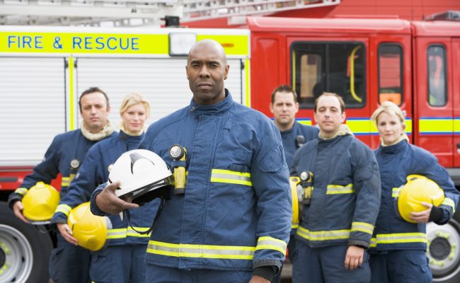 Portrait of a group of firefighters by a fire engine