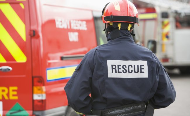 A firefighter standing by a small fire engine